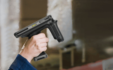 A person holding a lightweight RFID handheld reader in a warehouse environment, illustrating efficient asset tracking and inventory management.